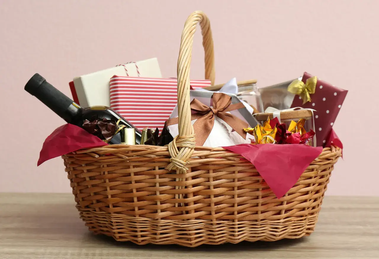 A wicker basket filled with gifts, including a bottle of wine, chocolates, and wrapped presents, perfect for cheap raffle prize ideas.