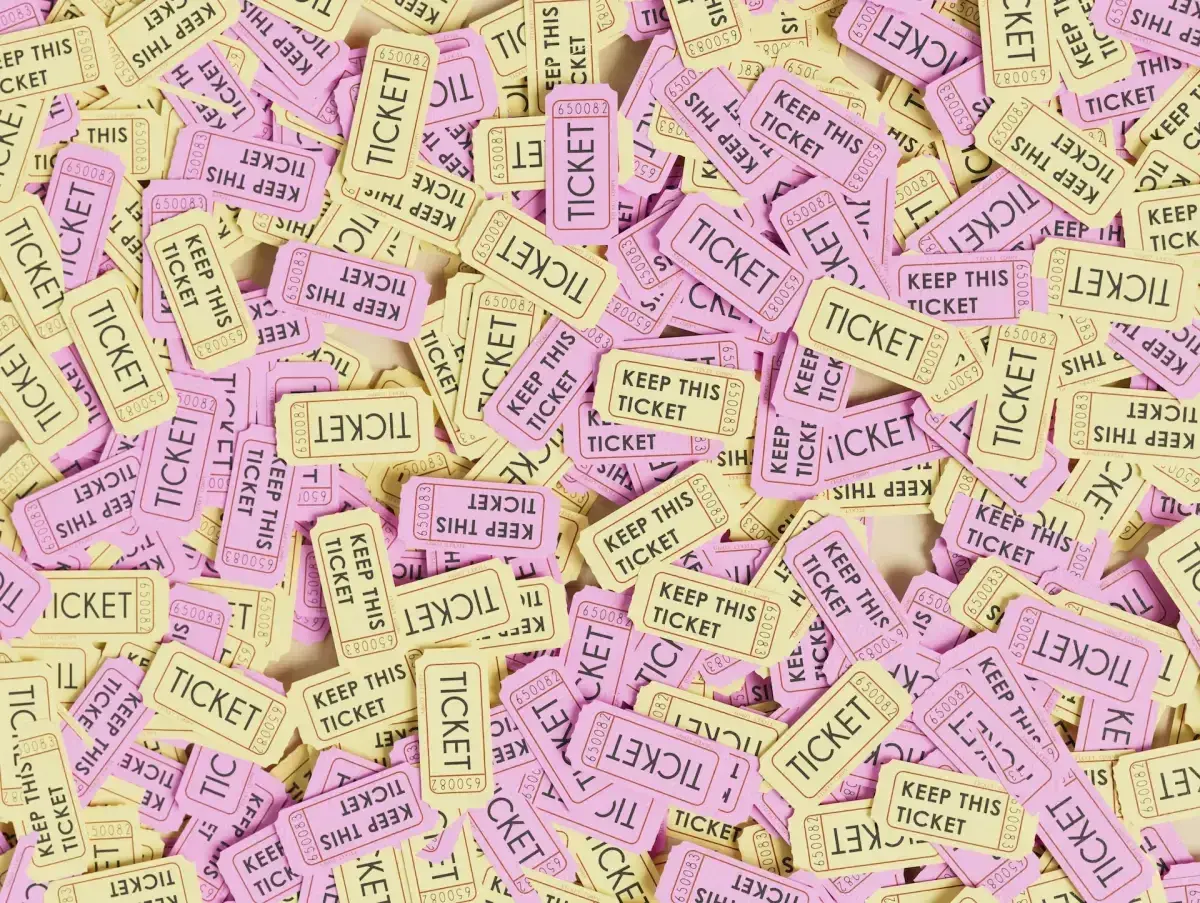 A pile of pink and yellow raffle tickets, some reading "KEEP THIS TICKET." This image might make you wonder, are raffles legal in Alabama?