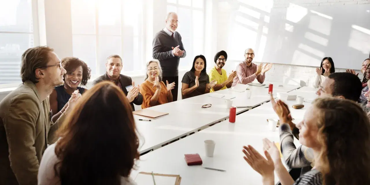Diverse group applauds at a meeting, perhaps discussing advisory board vs board of directors roles.
