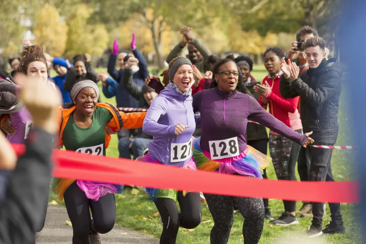 Runners cross the finish line at a fun charity event. This image shows how to start a charity event with enthusiastic participants and cheering crowds.