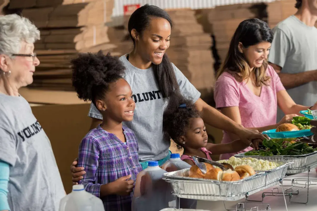 A student volunteer smiles as she helps serve food at a community event.