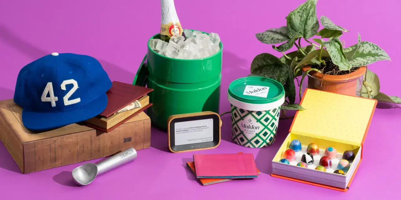 A blue baseball cap with "42" on it, books, a green ice bucket with a bottle, Maldon salt, an e-reader, a passport holder, and a box of chocolates. Small prize ideas for adults.