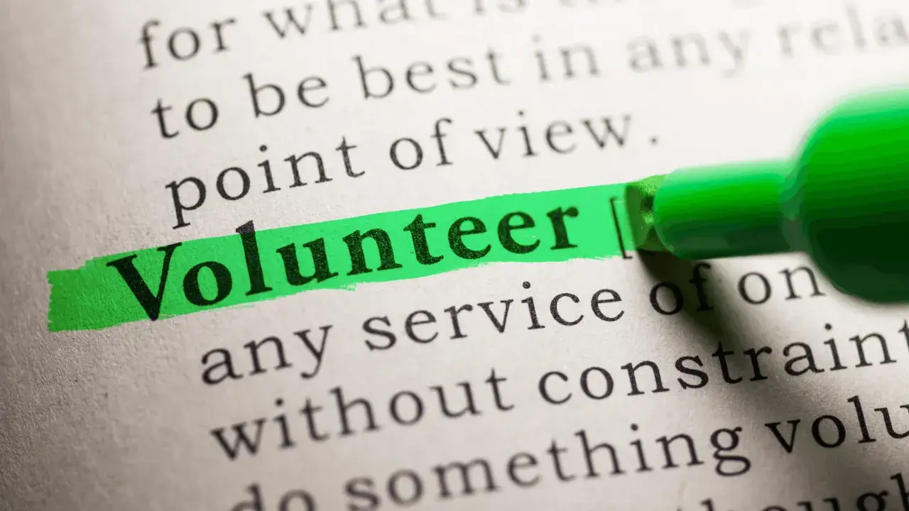 The word "Volunteer" is highlighted on a dictionary page, suggesting solutions to volunteering problems.