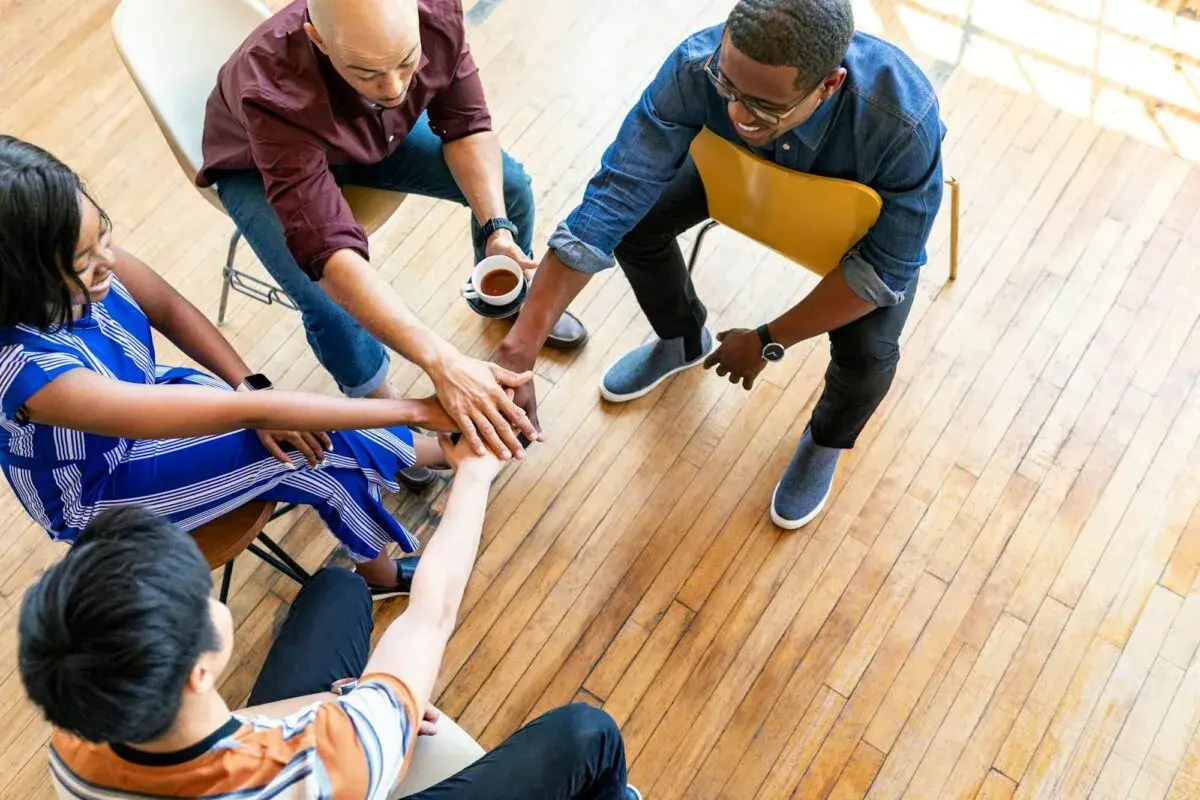 A diverse small group joins hands in a circle, symbolizing unity and collaboration for successful fundraisers.