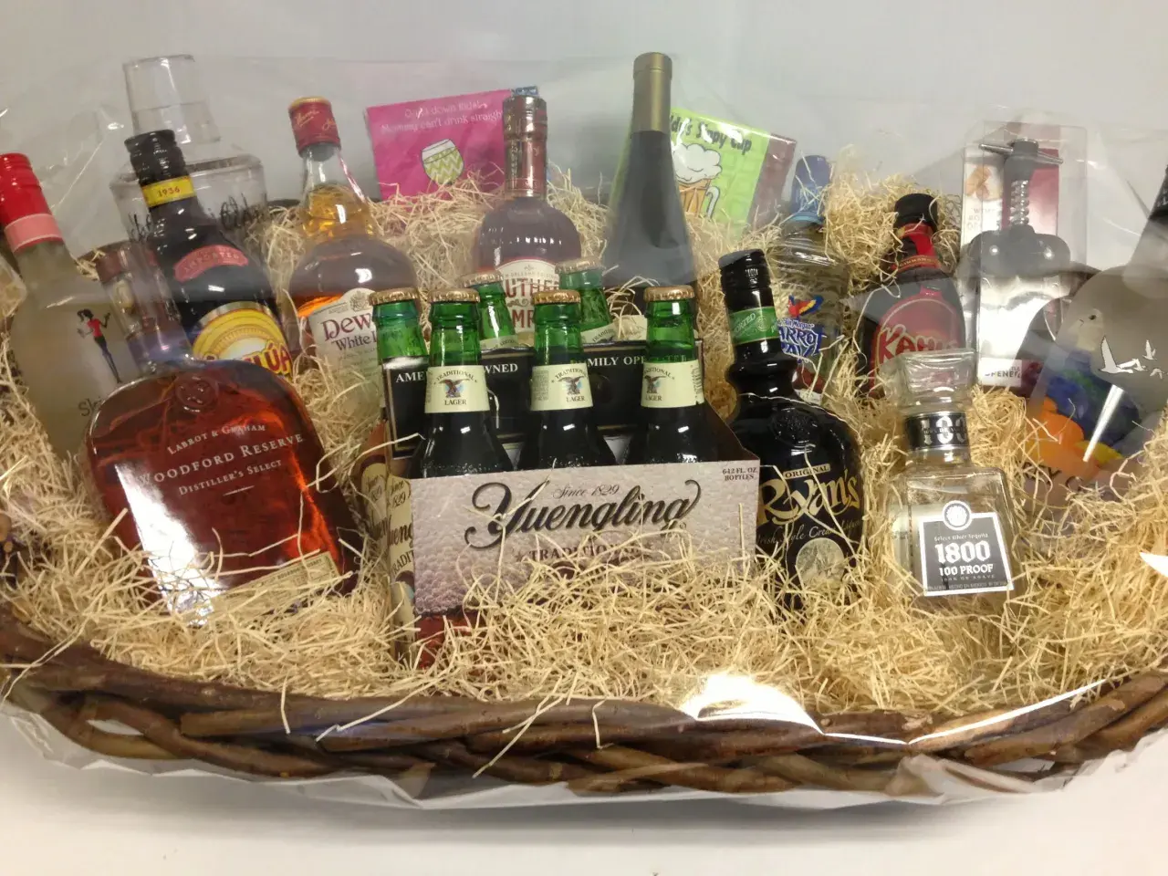 A festive basket filled with spirits and beer, perfect for unique charity gift basket ideas. Includes Woodford Reserve, Yuengling, and 1800 Tequila.