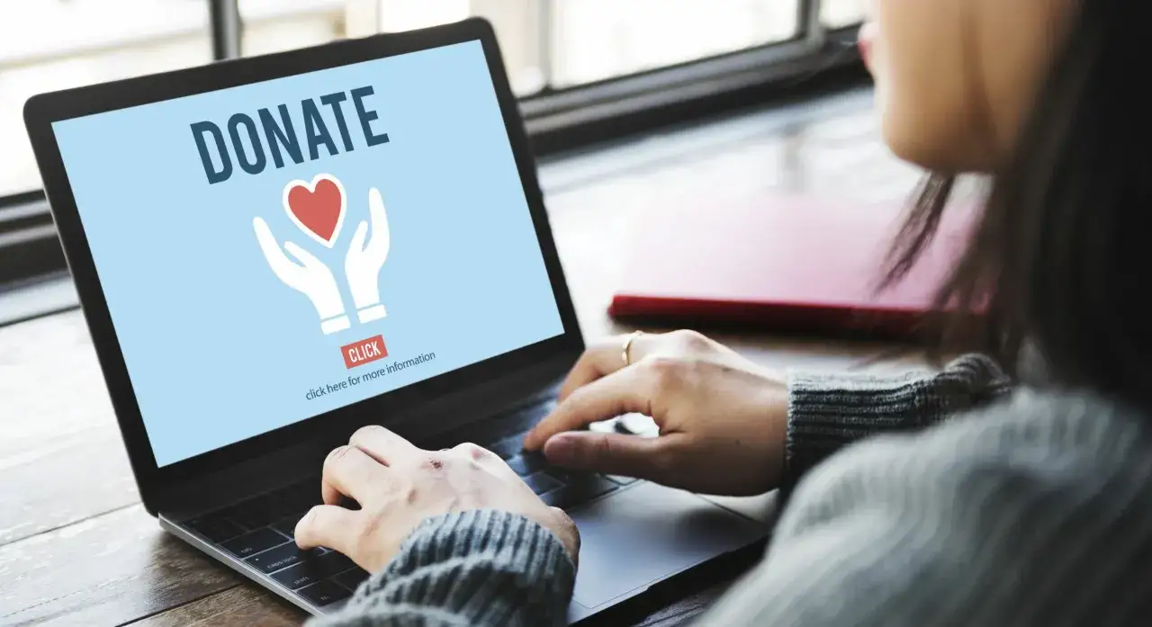 A person uses a laptop to explore free fundraiser ideas, with the screen displaying a 