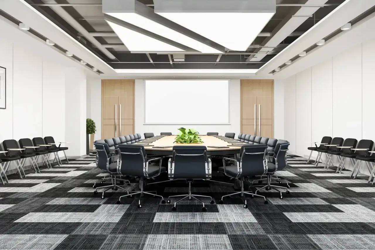 A modern board meeting setup with a large oval table, plush chairs, and a projector screen.