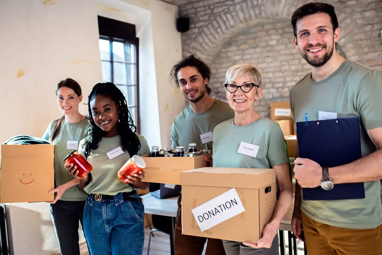 Volunteers smile, holding donation boxes and jars of food, embodying community fundraising efforts.