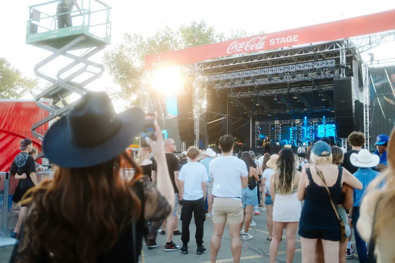 A crowd gathers for a concert on the Coca-Cola Stage. This scene captures the excitement of how to start a festival, with a band performing and attendees enjoying the music.