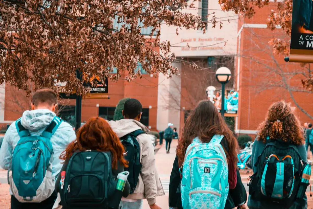 Students walk on campus, perhaps brainstorming college fundraiser ideas. A banner hangs in the background.