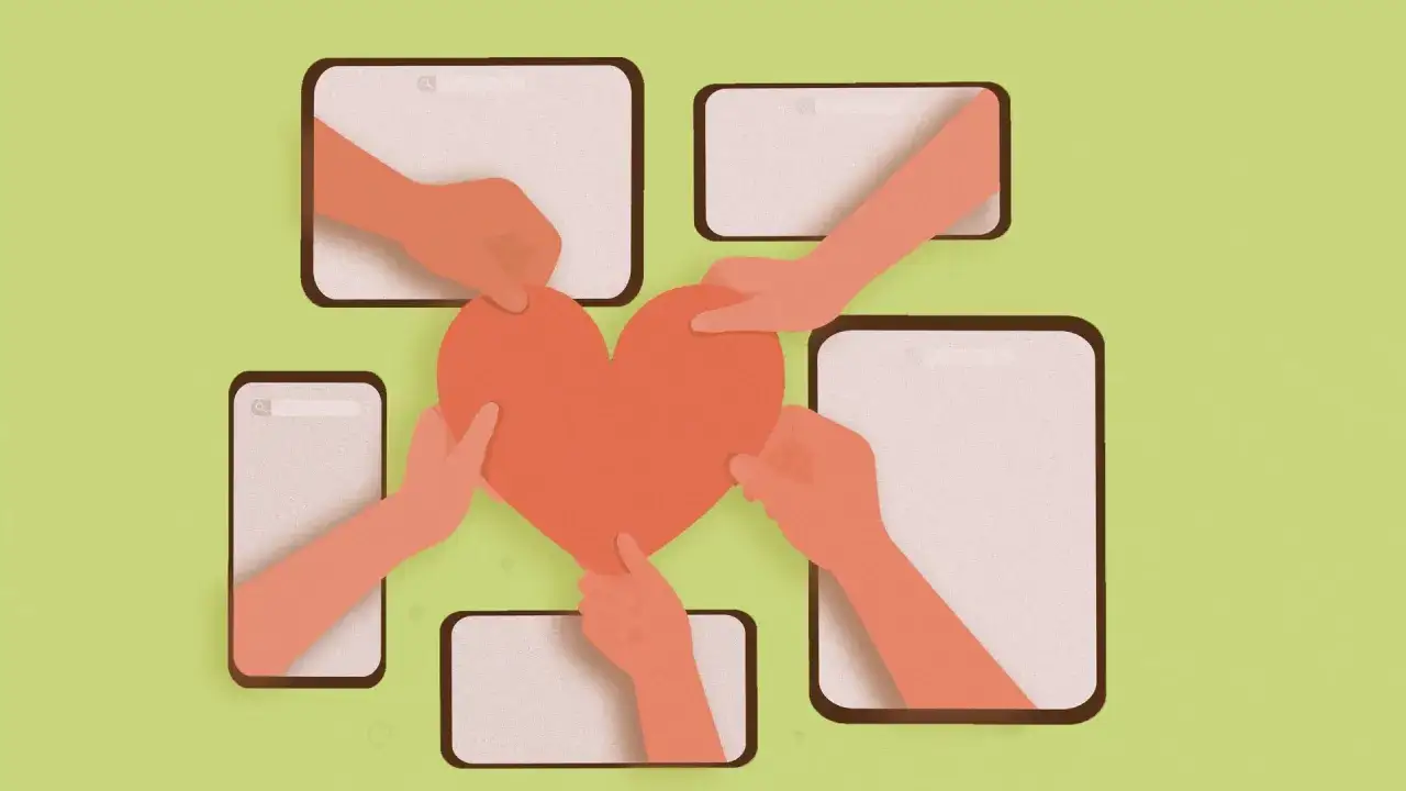 Hands reach from screens to hold a heart, symbolizing online volunteering and connection.
