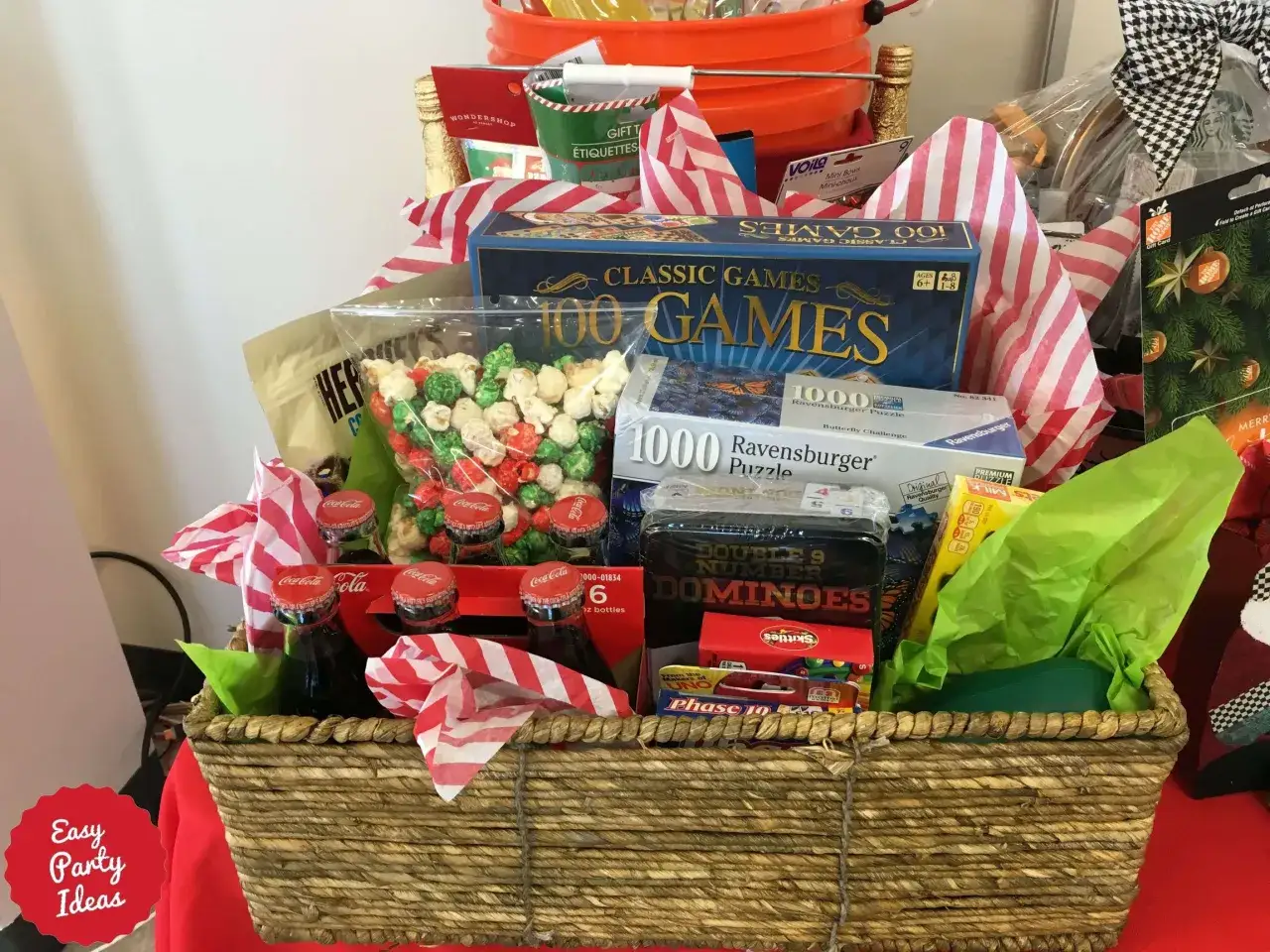 A woven basket overflows with raffle items: classic board games, puzzles, dominoes, popcorn, Coca-Cola bottles, and Hershey's treats, perfect for a fun-filled giveaway.