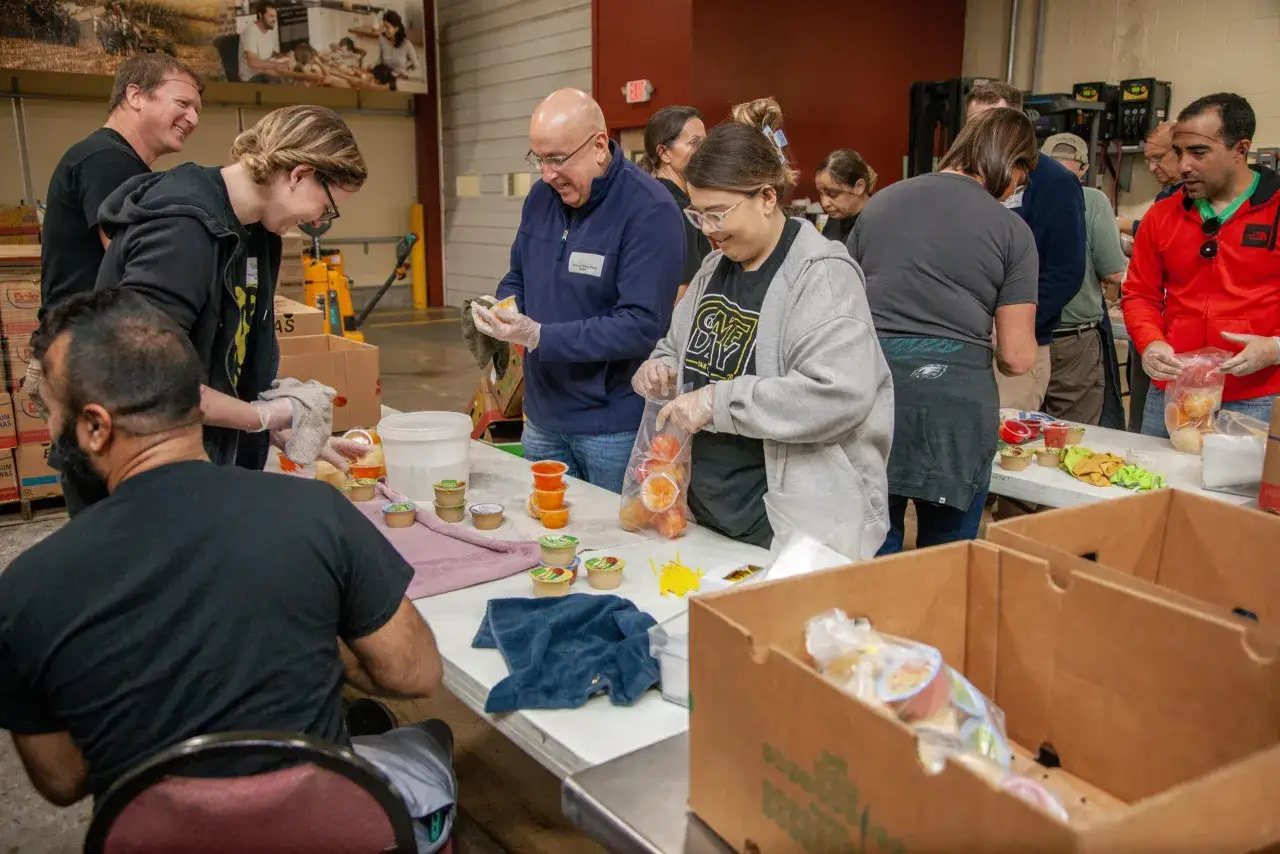 Volunteers pack food items, demonstrating what are service projects in action. They are preparing care packages for those in need.