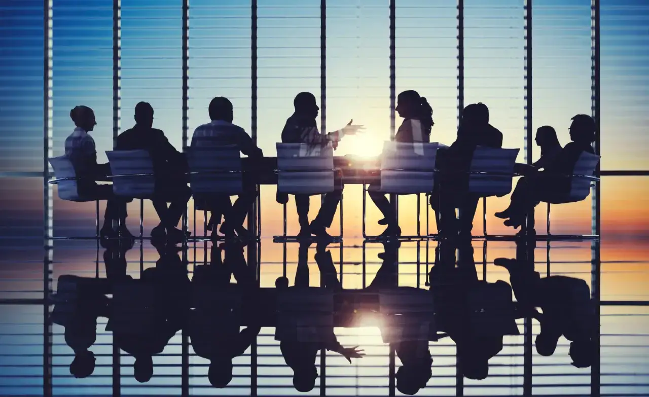 Silhouettes of people in a meeting, discussing the non profit board committee structure. Their reflections are visible on the polished floor.